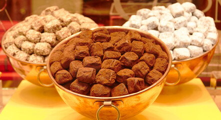 Three bowls filled with assorted Belgian chocolate truffles, showcasing rich textures and colors, including dark, milk, and white varieties, arranged beautifully for an enticing dessert display