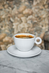 A white cup of black coffee americano in a cozy atmosphere of a cafe with copy space
