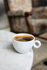 A white cup of black coffee americano in a cozy atmosphere of a cafe with copy space
