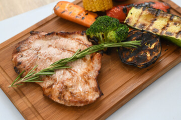 Grilled pork steak with vegetables on a wooden board