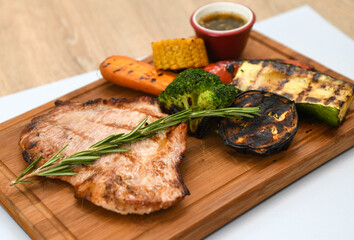 Grilled pork steak with vegetables on a wooden board