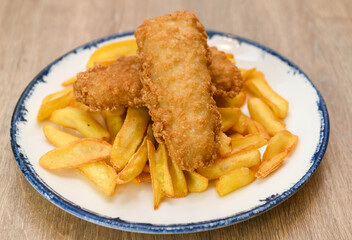 Fried fish fingers with french fries on a plate, close up