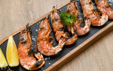 Grilled tiger prawns with lemon and parsley on wooden table