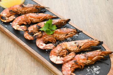 Grilled tiger prawns with lemon and parsley on wooden table