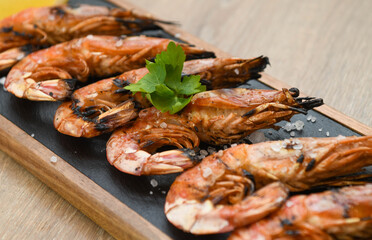 Grilled tiger prawns with lemon and parsley on wooden table