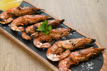 Grilled tiger prawns with lemon and parsley on wooden table