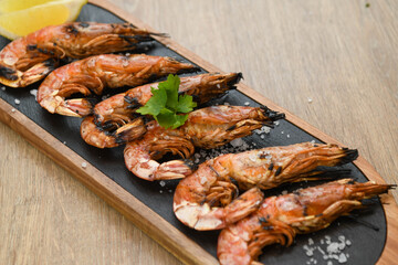 Grilled tiger prawns with lemon and parsley on wooden table