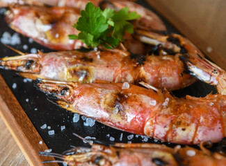 Grilled tiger prawns with lemon and parsley on wooden table