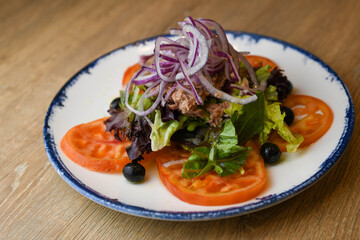 Salad with tuna, lettuce, red onion, black olives and tomato