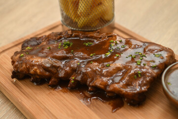 Pork ribs with sauce on a wooden board, close-up