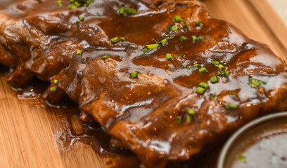 Pork ribs with sauce on a wooden board, close-up
