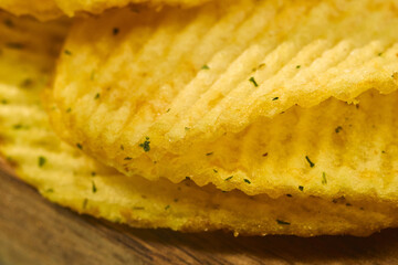 Crunchy potato chips stacked neatly with a golden hue and flecks of seasoning visible in close-up detail