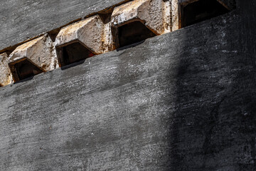 Industrial grey concrete wall with rectangular vents in shadow light