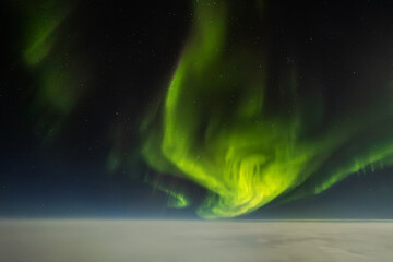 Aurora borealis seen from airplane cockpit over clouds at night