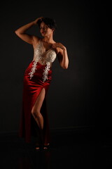 Full length low key portrait of pretty young dark haired woman in red classic evening dress