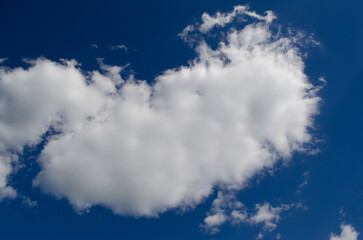 Fluffy white clouds float in a clear blue sky. The scene captures a serene and peaceful atmosphere, ideal for nature-themed projects.