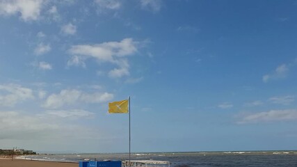 Stormy sea and yellow flag on lifeguard tower signal unsafe swimming conditions at the beach