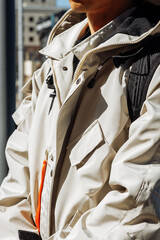 Man in white jacket with backpack - urban style and functionality in sunlight