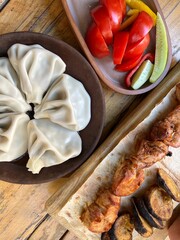 Top view Traditional Georgian dumplings, khinkali on a ceramic plate, shashlik and greens on a wooden table