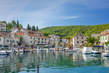 Obraz premium Calm Coastal Harbor With Boats and Waterfront Village Under Clear Blue Sky