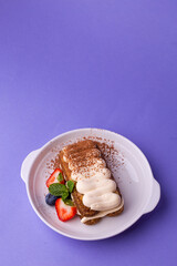 Tiramisu with berries and mint - classic dessert in white bowl on purple