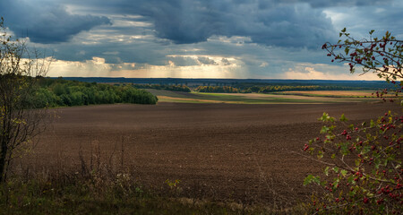 Arable field under a dramatic sky with rays of sunshine through the clouds at autumn