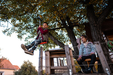 Little boy ziplining on a playground with sister