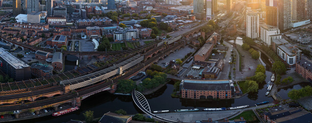 Panoramic sunrise aerial view of Castlefield in Manchester featuring the Bridgewater Canal, viaducts, and Merchants’ Warehouse.