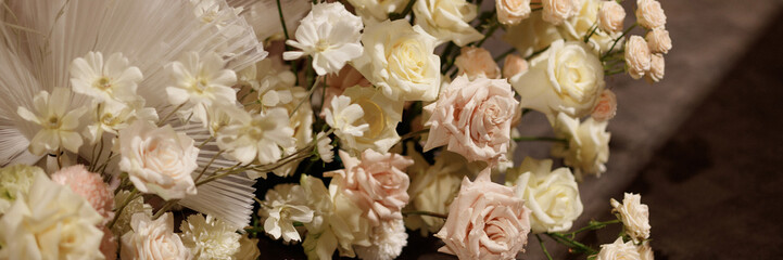 Wedding banquet table decorated with flowers, candles and food in festive hall with dark background. Concept of celebration, romance, event decoration, reception. Banner with copy space.