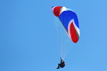 Paraglider flying in a blue sky	