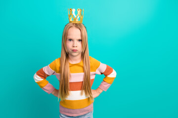 Adorable preteen girl wearing a striped sweater making a confident pose on a teal background