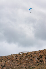 Parapente no reconocible con nubes y pared vertical junto al mirador del faro de Santa Pola, Espa&ntilde;a