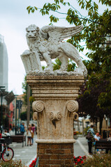 Weathered marble statue of the winged Lion of Saint Mark stands proudly in Venice, Italy; intricate detail showcases Venetian artistry. A majestic lion with outstretched wings atop an ornate column.