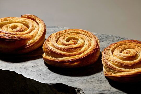 Freshly baked spiral pastries arranged beautifully on a dark stone surface