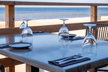 Elegant dining table set with glassware and cutlery, overlooking a serene beach view, creating a tranquil atmosphere for a memorable dining experience