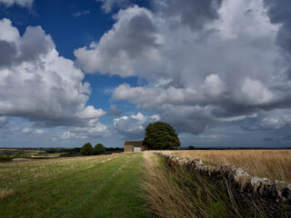 English landscape with clouds and old barn in the fields