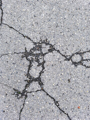 Intricate spiderweb pattern of cracks across gray asphalt road surface top view