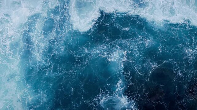 Ocean whitewater patterns across teal water, aerial top-down. Natural water texture for design and video backplates