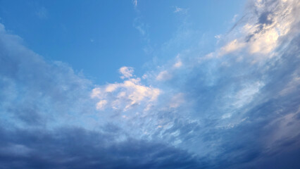 Obraz premium The dramatic day ends with Altocumulus-Cirrocumulus layers catching sunset light, transitioning from gray to serene pink and blue hues, signaling complete atmospheric stability