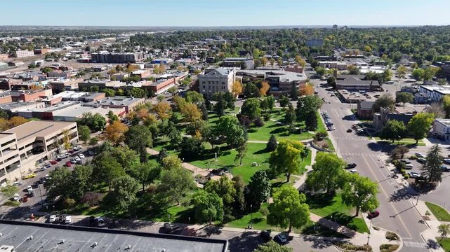 Aerial view of Lincoln Park, a lush green space surrounded by buildings and streets with parked cars, reflecting the city's vibrant life, Greeley, Colorado, United States.