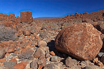 Rocky, dry landscape featuring boulders under a cloudless blue sky