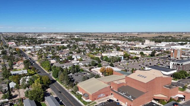 Aerial view of a vibrant cityscape featuring lush green parks and bustling streets under a clear blue sky, Greeley, Colorado, United States.