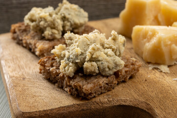 Matured strong british blue cheese stilton keeping in ceramic bowl under wax layer, cheese and whiskey pairing