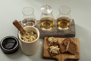 Matured strong british blue cheese stilton keeping in ceramic bowl under wax layer, cheese and whiskey pairing