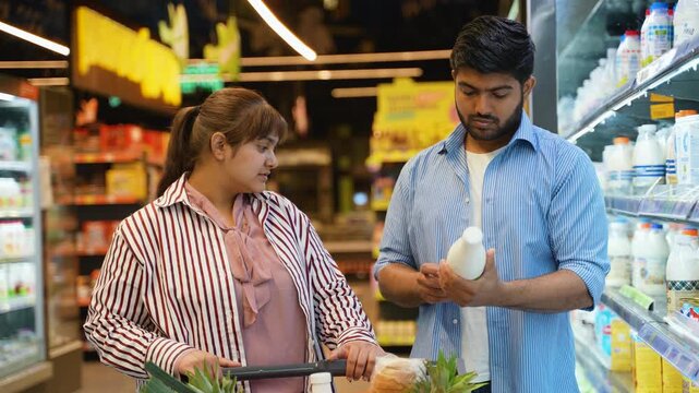 Indian couple buying milk in the supermarket dairy section