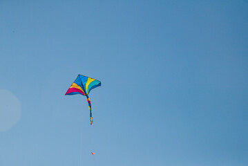 Colorful kite flying high in blue sky