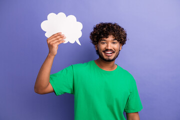 Young man in green shirt holding speech bubble cutout against purple background showing...