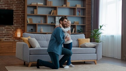 Obraz premium Portrait Caucasian happy family in living room daughter and father hugging cuddling smiling dad standing on knee hug cute child lovely kid girl cuddle embracing at home cheerful Father's day custody