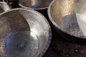 Metallic bowls are arranged in a Moroccan market, showcasing traditional craftsmanship. The bowls reflect light and highlight intricate designs and textures