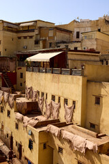 In Fes, Morocco, traditional buildings with yellow walls stand out against the blue sky. Laundry hangs outside as locals go about their day in this vibrant city